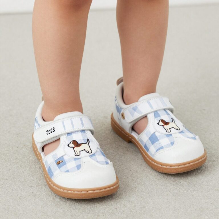흰색 바탕에 체크 패턴과 강아지 자수가 있는 닥스키즈 실내화를 신은 어린이 발