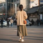 베이지 루즈핏 야상점퍼를 스커트와 함께 코디한 여성의 뒷모습