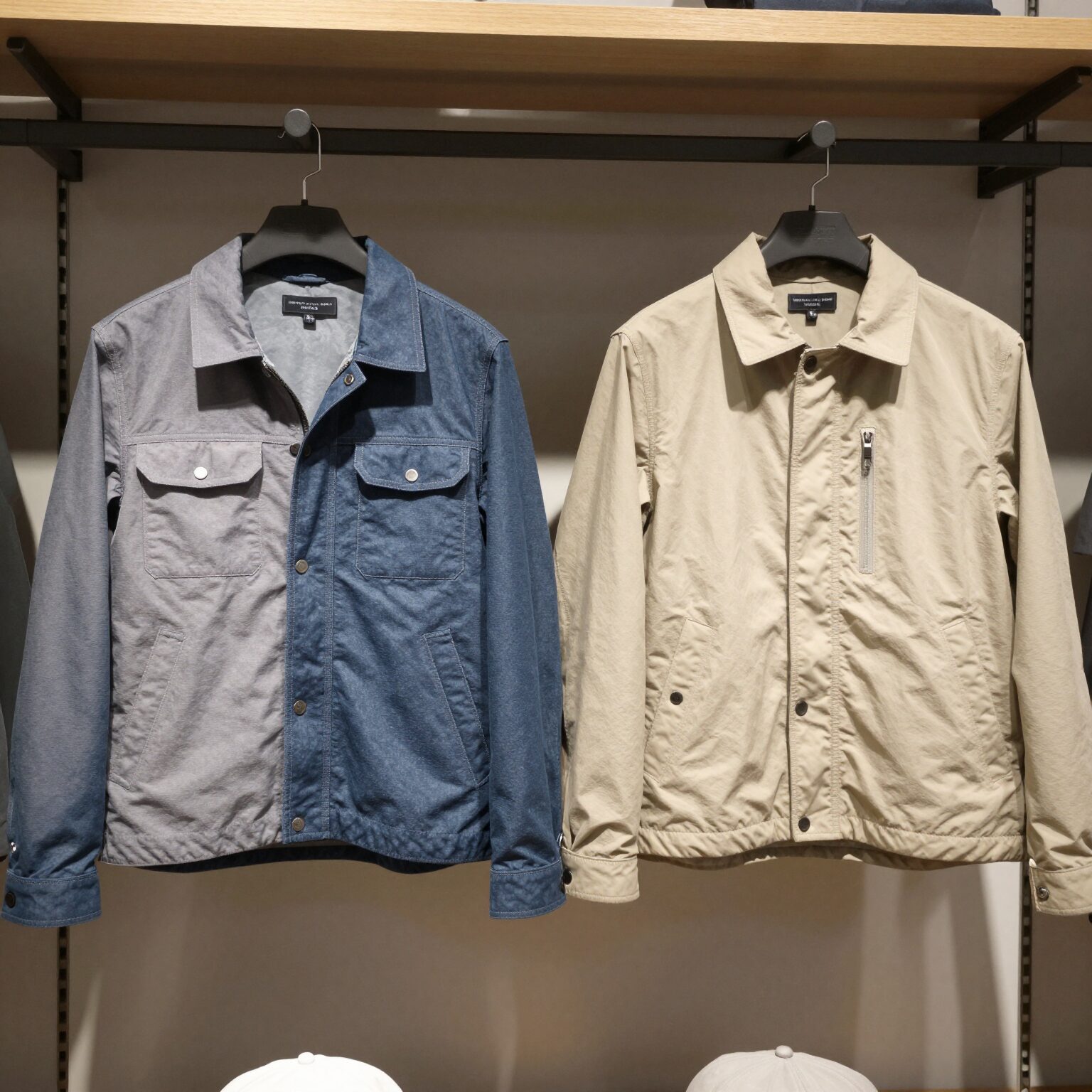 두 가지 다른 소재의 워크자켓이 매장 레일 위에 걸려 있는 모습