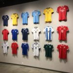 다양한 색상과 디자인의 축구 유니폼이 벽에 걸려 있는 모습