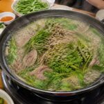 담양 오리 맛집 3곳 비교 정리 담양 오리 맛집 유진정의 청둥오리전골이 끓는 모습으로 솥 안에 오리고기와 미나리, 들깨가루가 보이며 주변에 밑반찬과 소스가 세팅되어 있다.