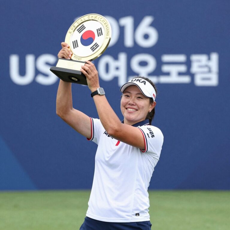 2026 US여자오픈 우승자가 트로피를 들어 올리며 기뻐하는 모습. 배경에는 갤러리와 푸른 필드가 펼쳐져 있다.