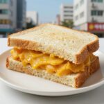 완성된 단호박 샌드위치를 접시에 담아 옆면이 보이게 촬영한 사진, 노란 단호박 페이스트가 식빵 사이에 가득 차 있다