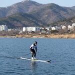 충주 수상스키 완벽 정리 충주호에서 수상스키를 타는 사람이 활공하는 모습, 배경은 맑은 호수와 푸른 산
